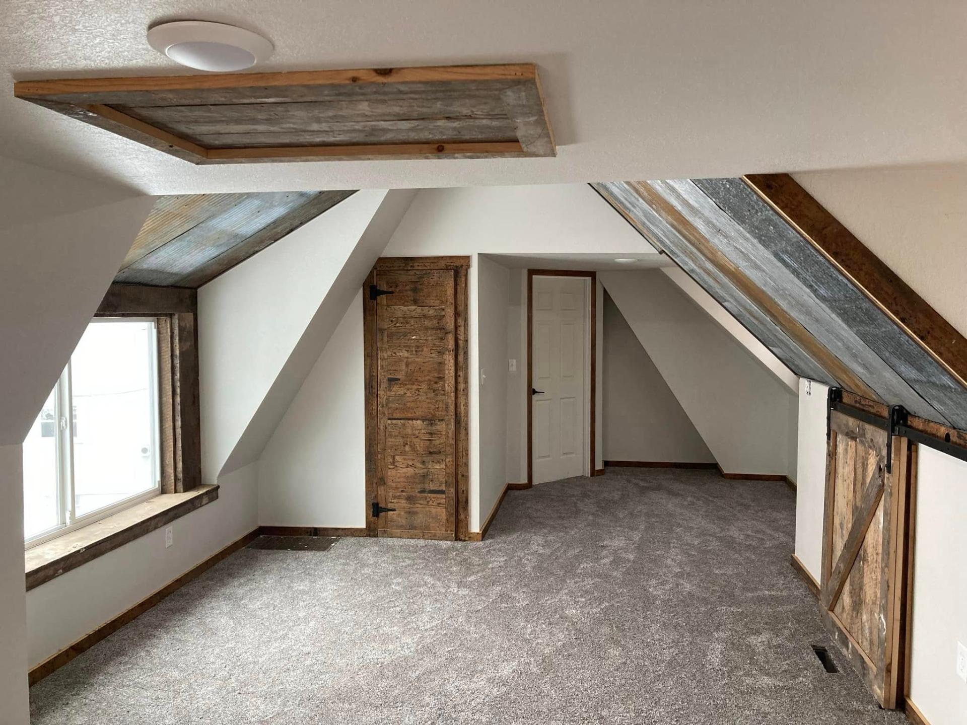 Finished attic bonus room with reclaimed barnwood accents and sliding barn door