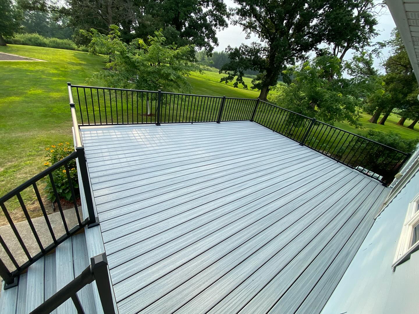 Two-tone composite deck with black aluminum railing overlooking open field