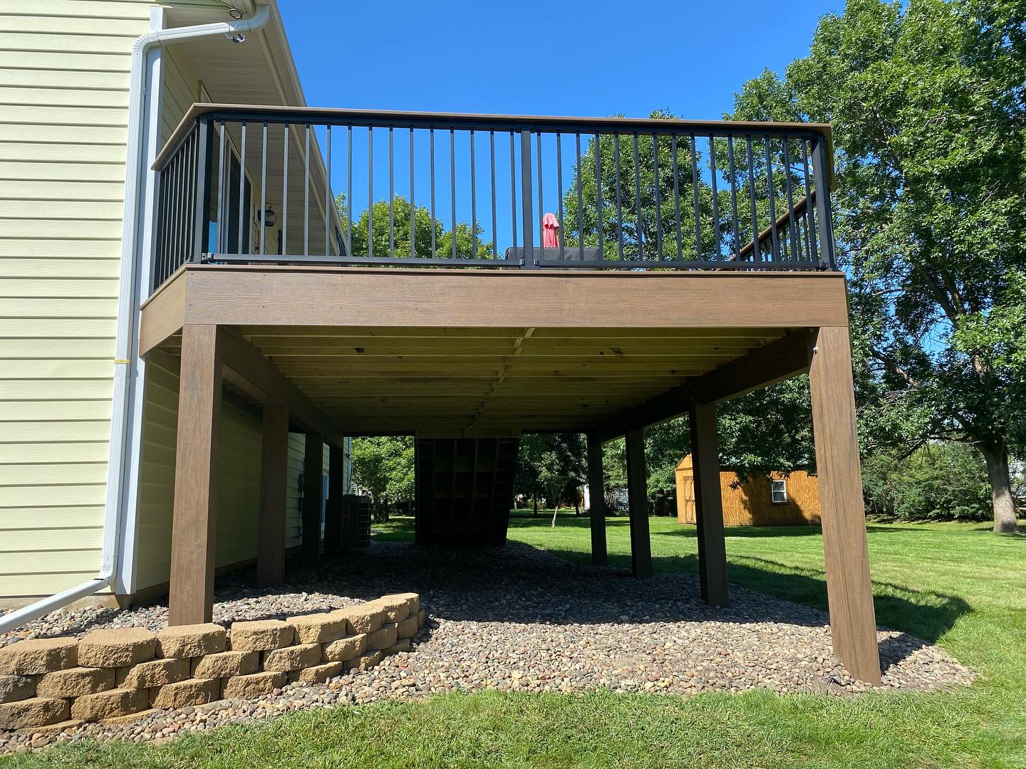 Tall elevated composite deck with under-deck storage and stone landscaping
