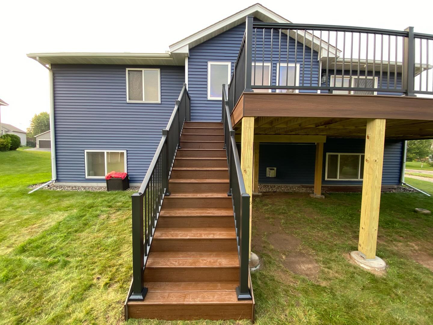 Elevated deck with stained stair treads on a navy-blue two-story home