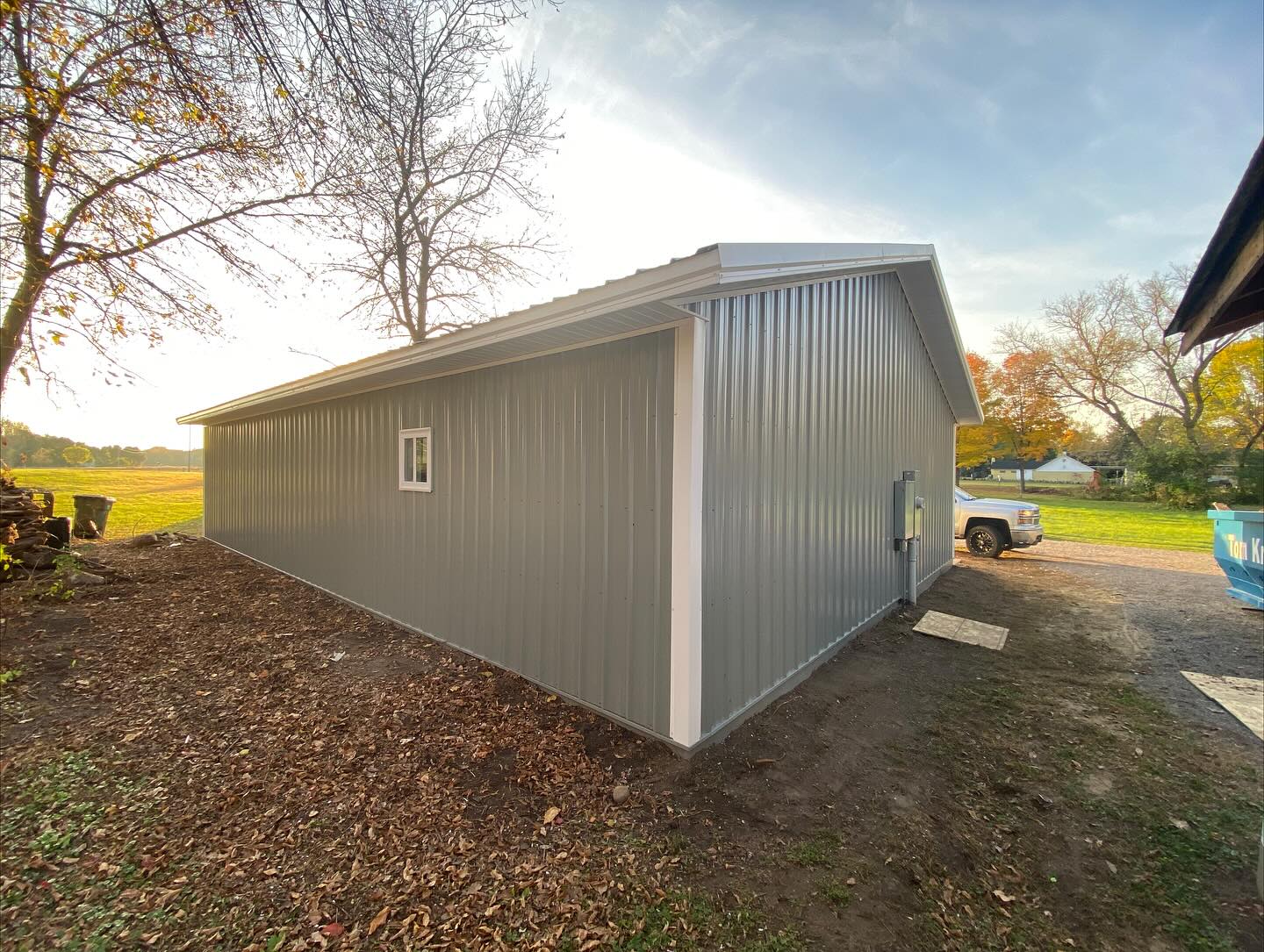 Side profile of a freshly built gray steel pole barn at sunset