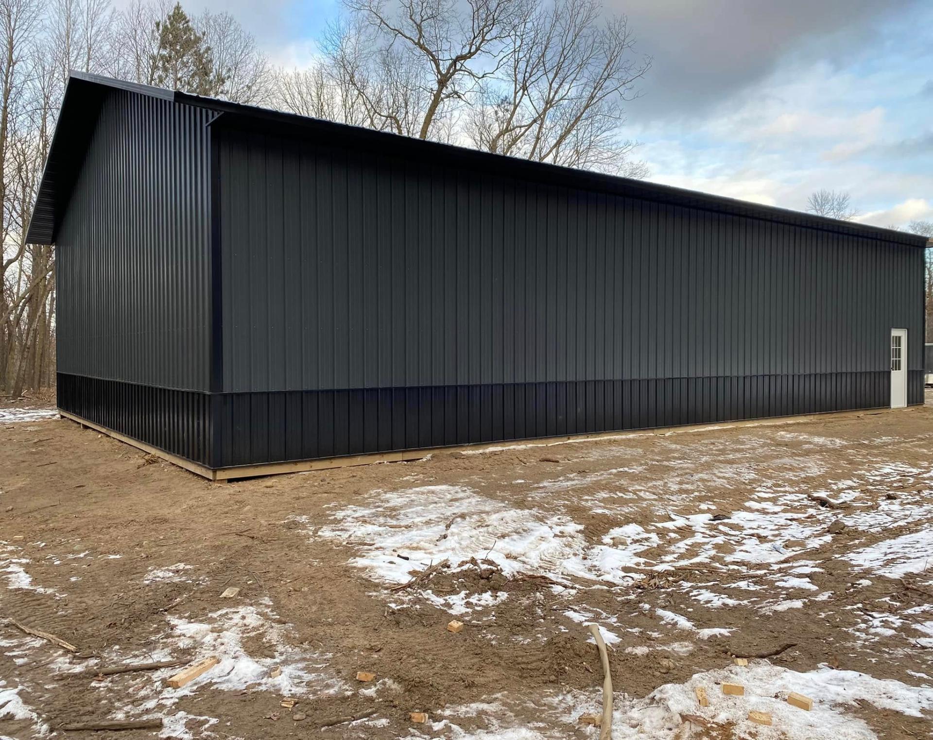Long side wall of a new black steel pole-frame warehouse